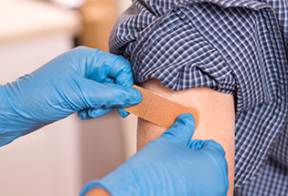 Photograph of a person getting a bandage applied after receiving a shot from a medical professional